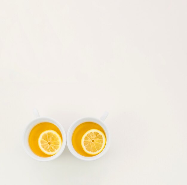 흰색 배경에서 레몬 슬라이스와 녹차의 두 컵