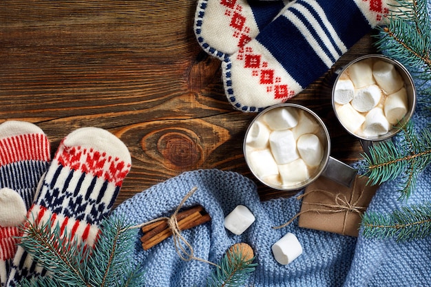 Two cups of hot cocoa or chocolate with marshmallow, mittens, christmas decor and fir tree on wooden rustic background from above. Flat lay style.. New year 2018