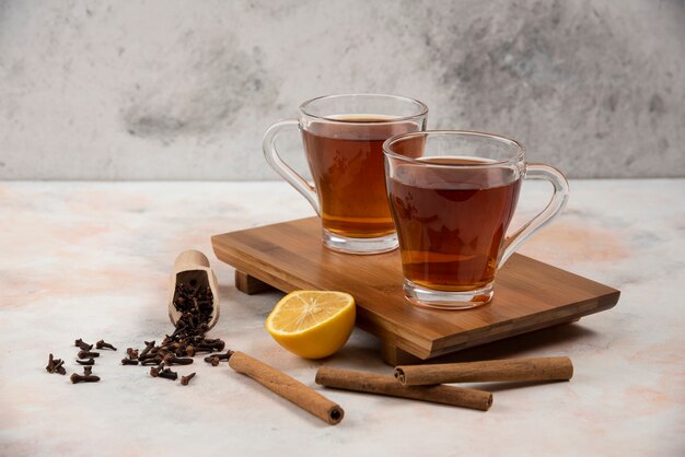 Two cups of hot tea on wooden board with cinnamon sticks. 