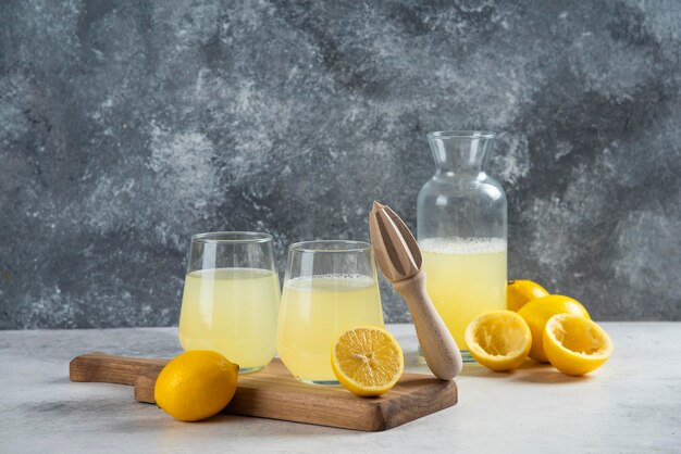 Two cups of lemon juice on a wooden board.