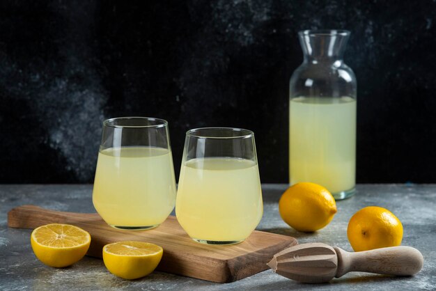 Two cups of lemon juice on wooden board.