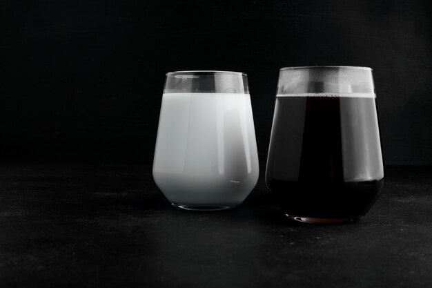 黒の背景に牛乳と濃いエスプレッソの2つのカップ。