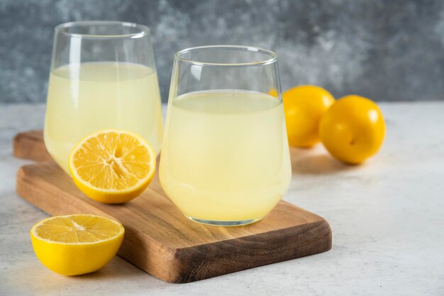 Two cups of tasty lemonade on a wooden board.