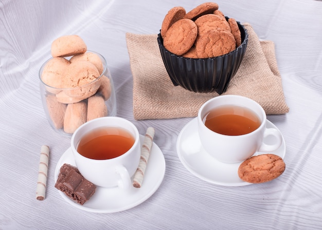 Two cups of tea with biscuit and chocolate