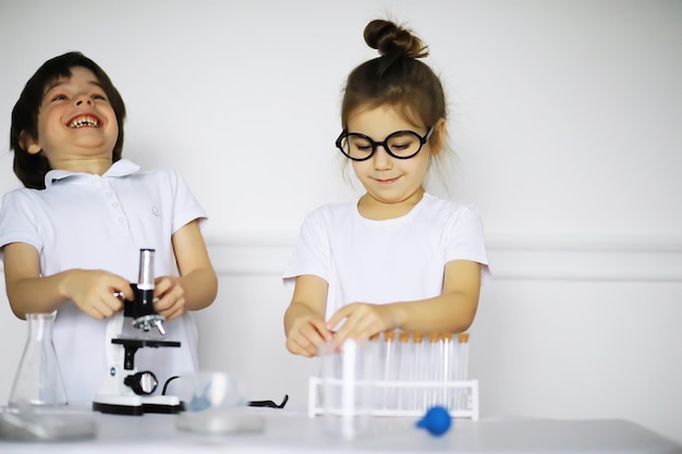 Двое милых детей на уроке химии проводят эксперименты, изолированные на белом фоне