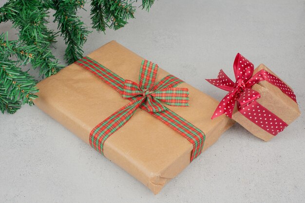 Two cute gift boxes with green tinsel on gray surface.