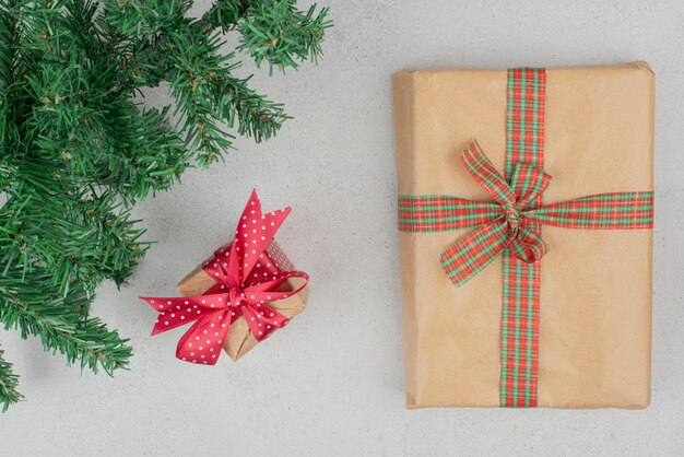 Two cute gift boxes with green tinsel on gray wall.