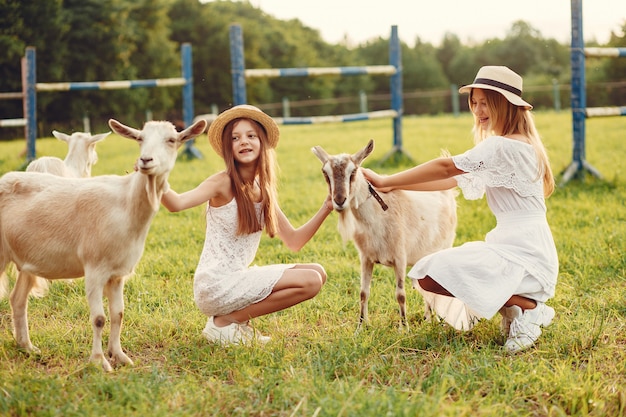 Free photo two cute girls in a field with a goats