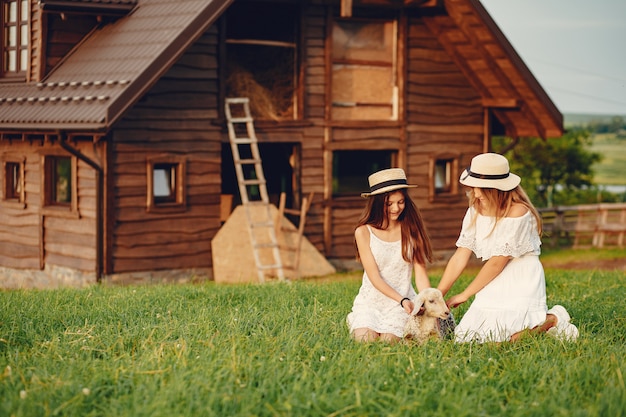 Two cute girls in a field with a goats