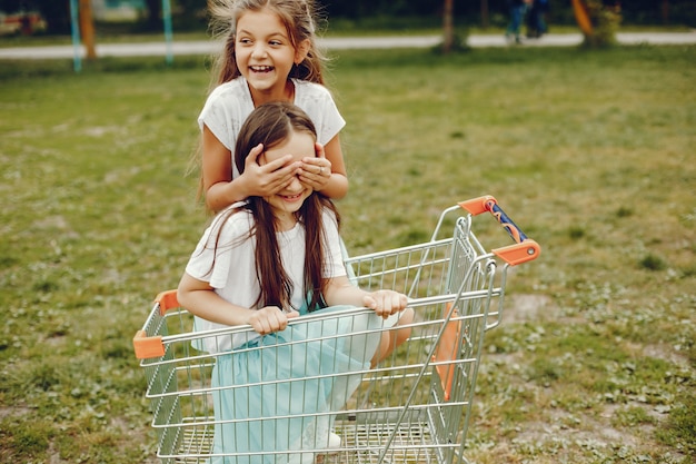 Free photo two cute little girls in white t-shirts and blue skirts play in the summer park ride