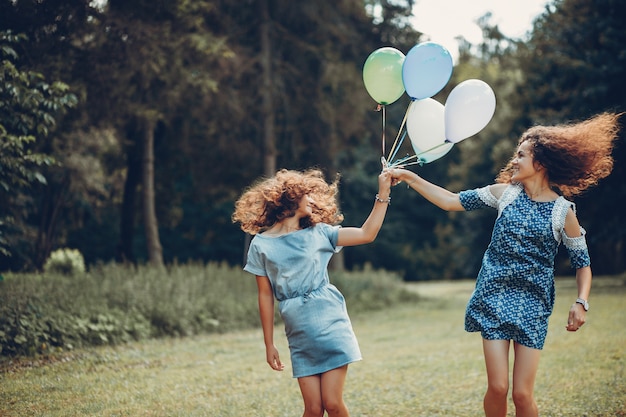 Free photo two cute sisters in a summer park