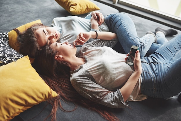 Two cute smiling twins sisters holding smartphone and making selfie.