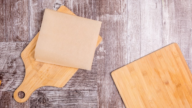 Two cutting wodden plates on wooden backgorund. One is covered with cooking paper