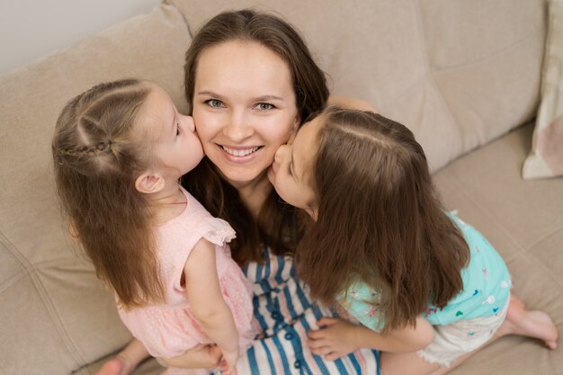 Two daughters kissing their mommy