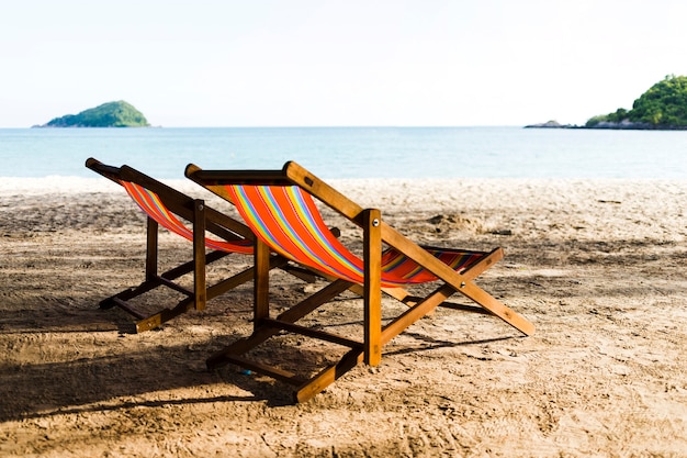 Two deckchairs on sandy beach