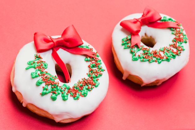 Two decorated donuts arranged on red background