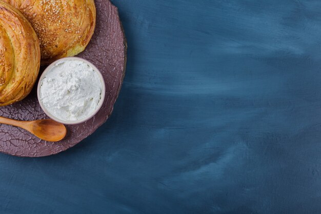 Two delicious traditional pastries and sour cream on wood piece.