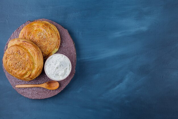 Two delicious traditional pastries and sour cream on wood piece.