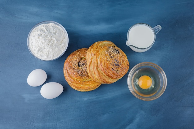 Two delicious traditional pastries with flour and milk on blue surface. 