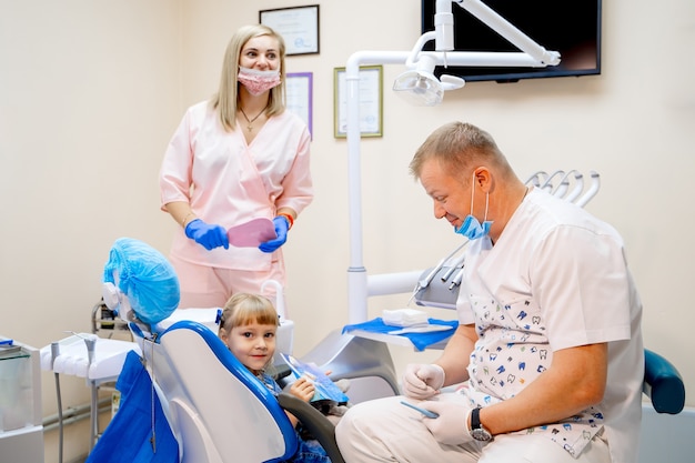 Two dentists examine kid s patient teeth for the further treatment. modern stomatology cabinet.
