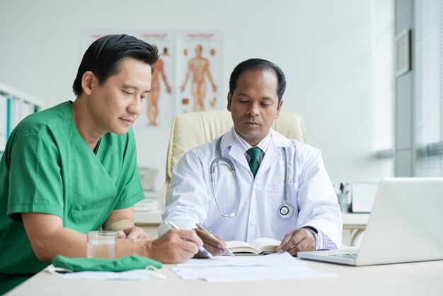 Two Doctores Working Together Sitting At Desk