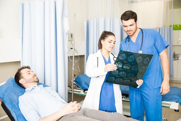 Two doctors analyzing CT scan results of a patient during visit in emergency room