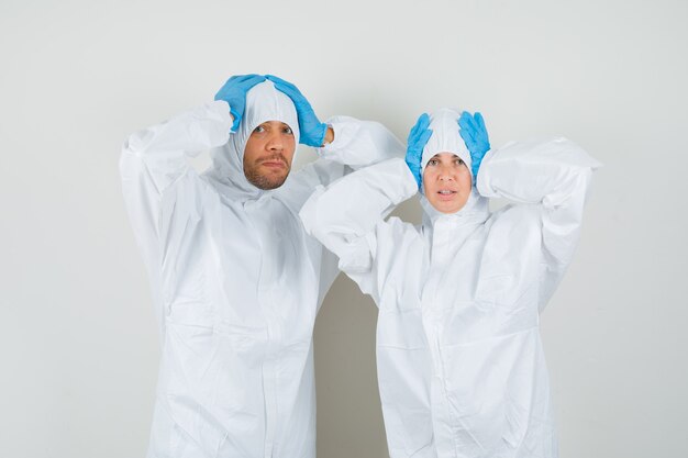 Two doctors clasping head with hands in protective suits