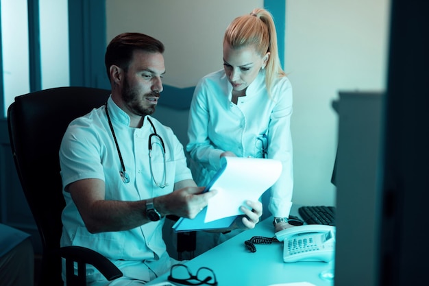 Two doctors cooperating while reading patient's medical documents in the hospital