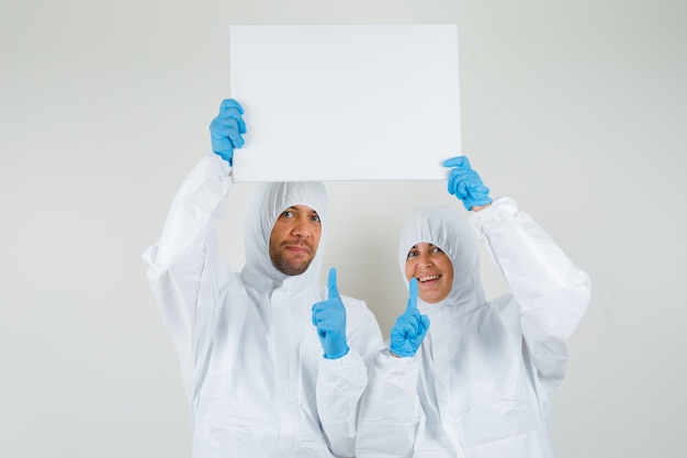 Two doctors pointing at blank canvas in protective suits