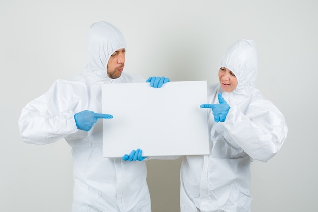Two doctors pointing at blank canvas in protective suits