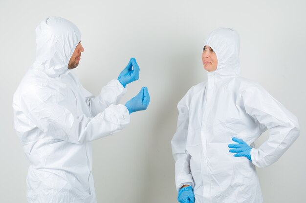 Two doctors in protective suit, gloves discussing something and looking merry