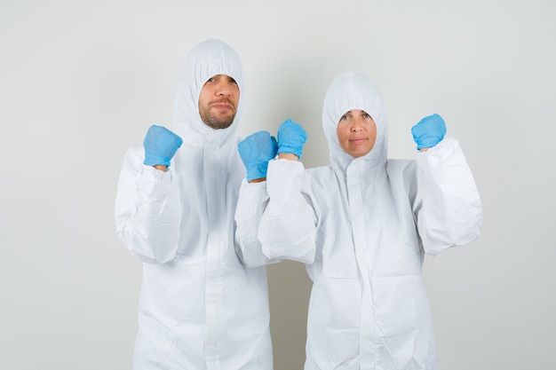 Two doctors in protective suits, gloves showing clenched fists and looking strong