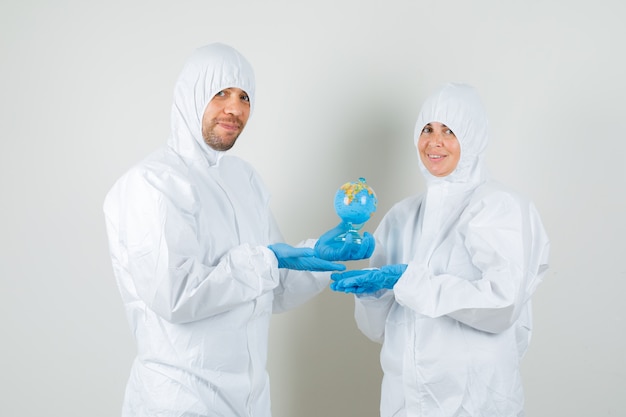 Two doctors showing globe model in protective suits