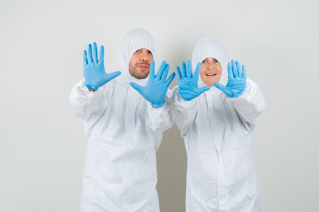 Два врача в защитных костюмах показывают жест отказа