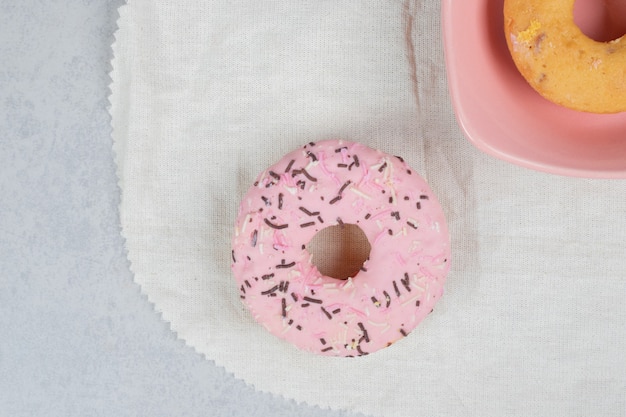 Two donuts with sprinklers on marble table. High quality photo