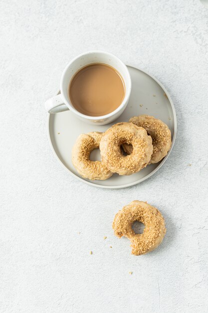 Two doughnuts on white ceramic plate beside white ceramic mug