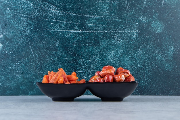 Free photo two dried organic fruits on black plate on stone background.