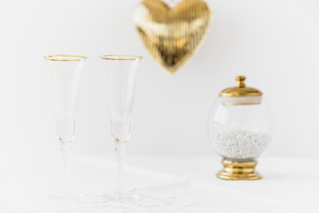 Two drinking glasses and mouth freshener in glass container on table