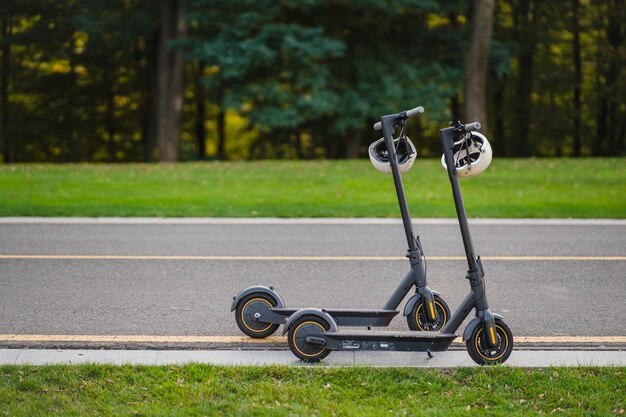 Two electric kick scooters or e-scooter parked on the sidelines road