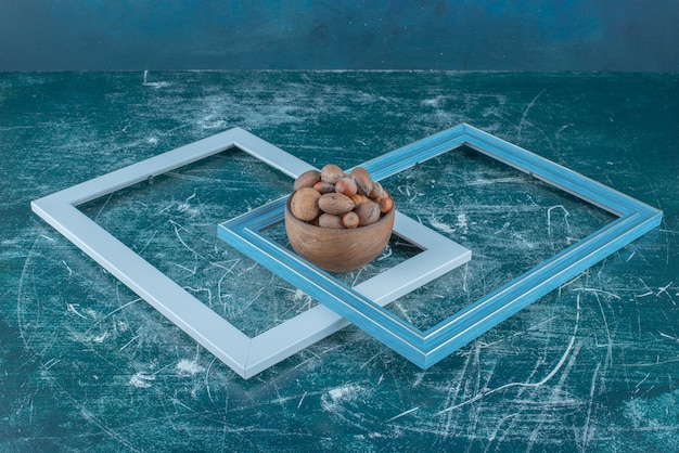 Free photo two empty frames and a bowl of assorted nuts on blue background. high quality photo