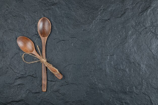 Two empty wooden spoons on a dark background. 