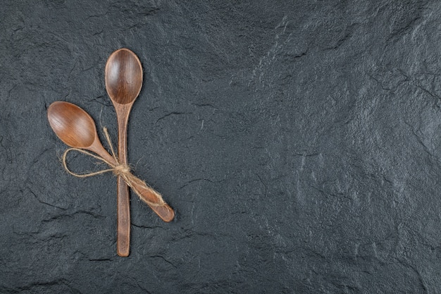 Two empty wooden spoons on a dark background. 