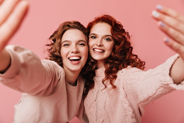 Free photo two excited girls having fun together. adorable young ladies gesturing on pink background.