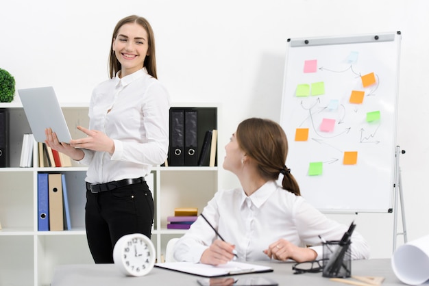 Two female colleague looking at each other while working in the office