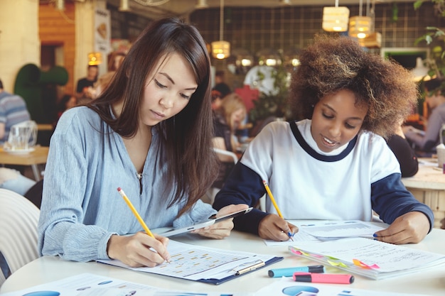 Two female coworkers working together in cafe