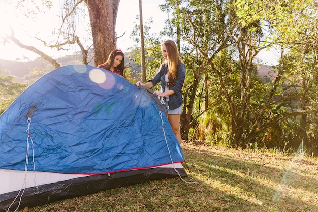 캠핑 동안 텐트를 준비하는 두 여자 친구