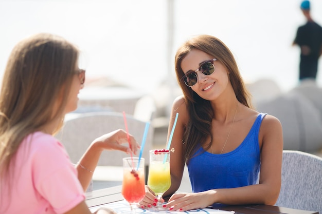 two female friends in cafe with drinks outdoors