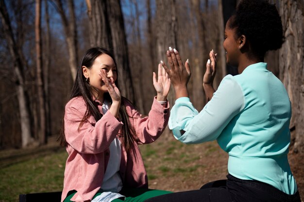 Free photo two female friends celebrating the lifting of face mask restrictions outdoors