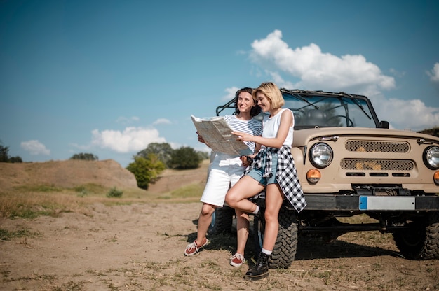 Free photo two female friends checking map while traveling by car