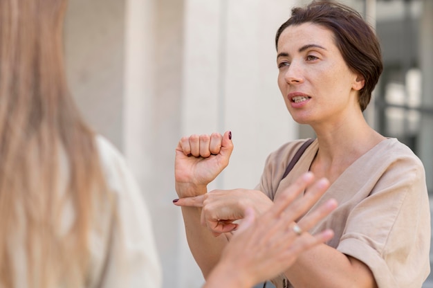 Two female friends conversing outdoors using sign language